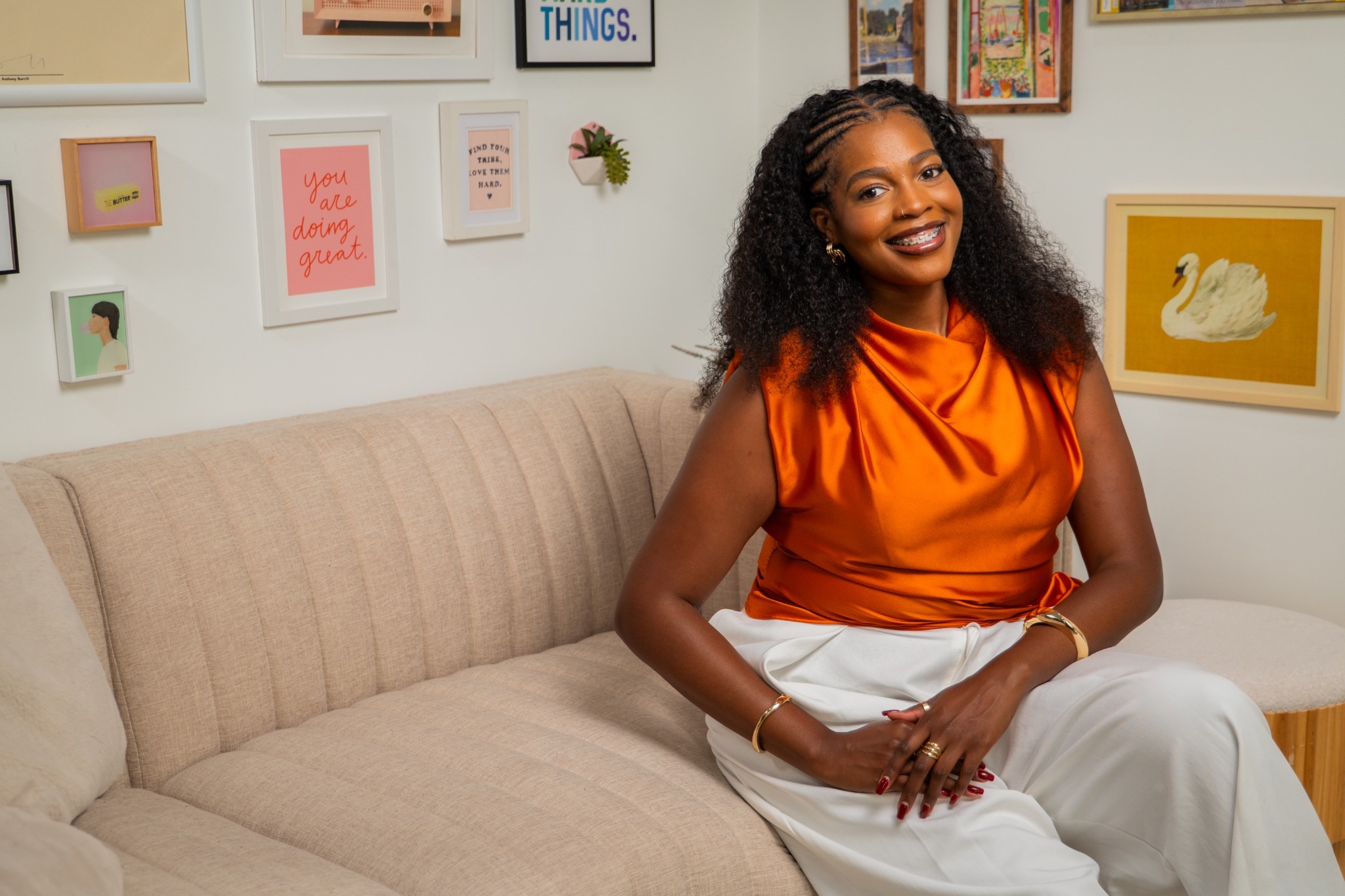 Kylah Williams smiling while sitting on a beige sofa in an office with framed artwork.